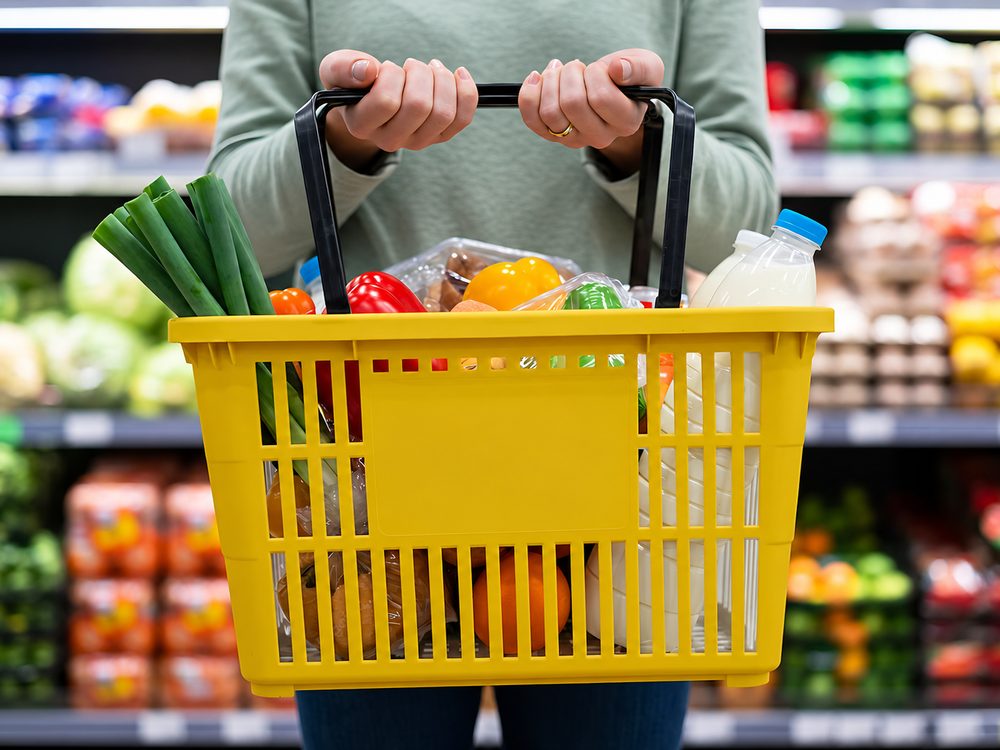 Persona sosteniendo una canasta amarilla con productos en un comercio