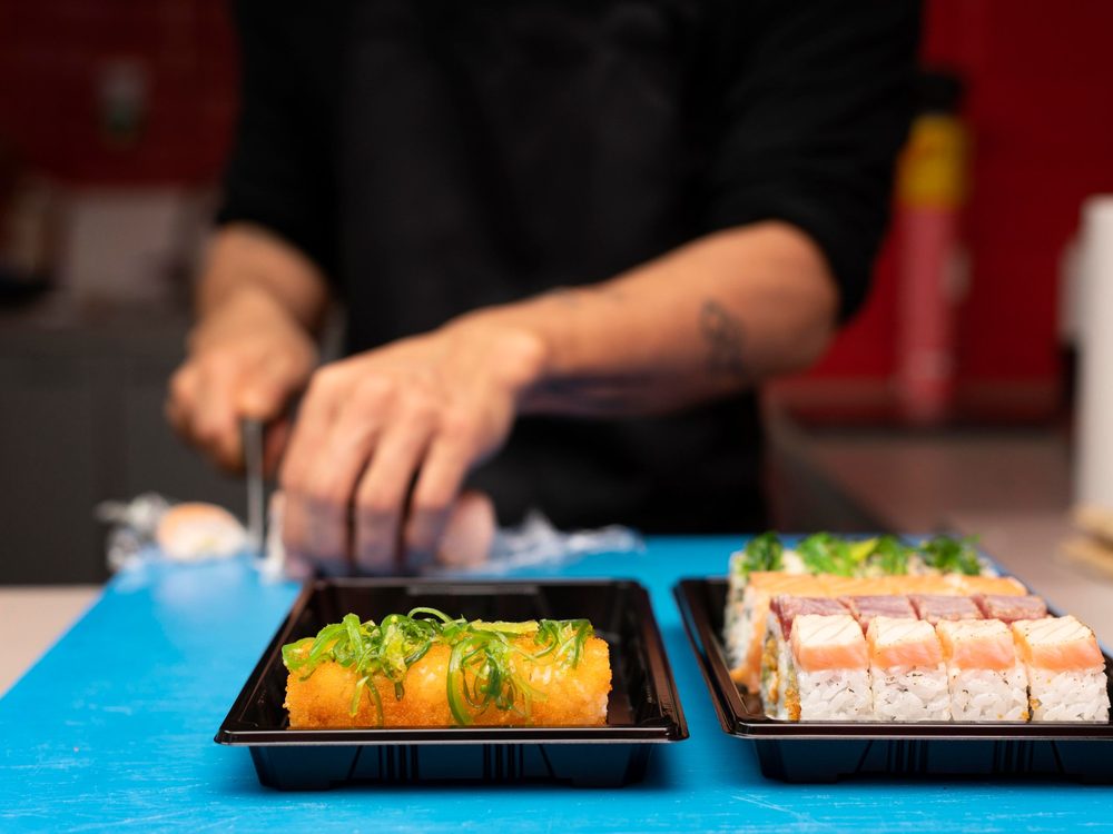 Rolls de sushi en bandejas negras para llevar